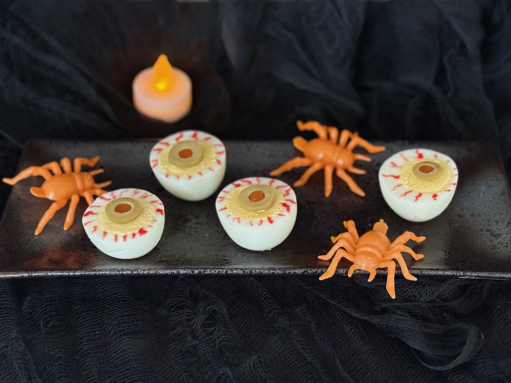 Cut boiled eggs in half crosswise. Make squiggly lines with a toothpick dipped in food coloring on the egg whites and top with a slice of pimento-stuffed olive to make blood-shot eyes.