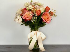 A flower bouquet is made by gathering flowers, securing with a rubber band, and snipping stems to fit the vase.