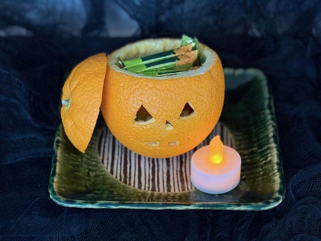Jack-o-lantern is carved from an orange; fill with candy and a tea light.