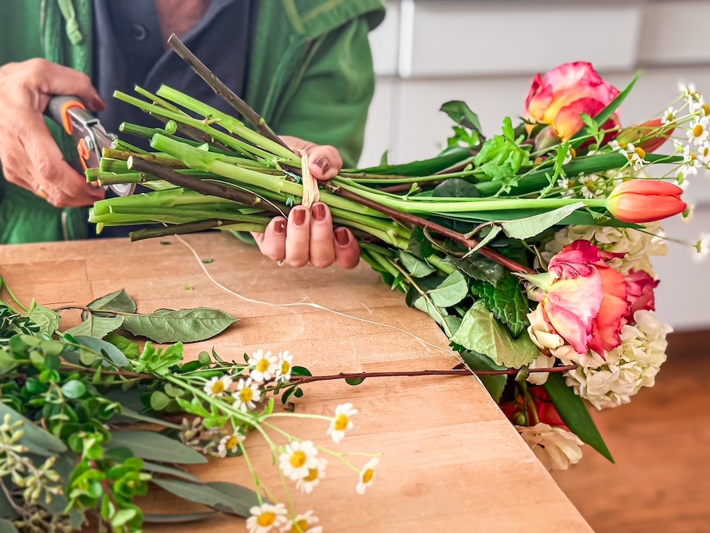 After flowers have been rubber banded into a bouquet, trim stems to fit the vase.