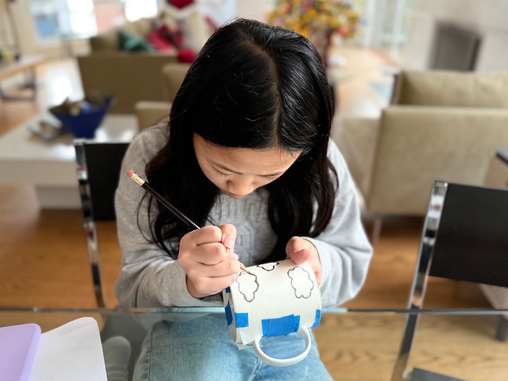 Child decorates a mug for her father's gift. Prep for the holidays by having kids make their gifts well ahead of Christmas.