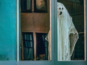 Almost life-size cheesecloth ghost hovers in a window.