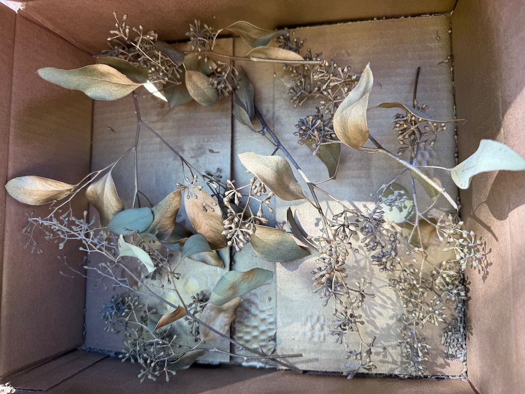 Gold-sprayed eucalyptus leaves. They were sprayed in a box to avoid paint getting on the work surface.