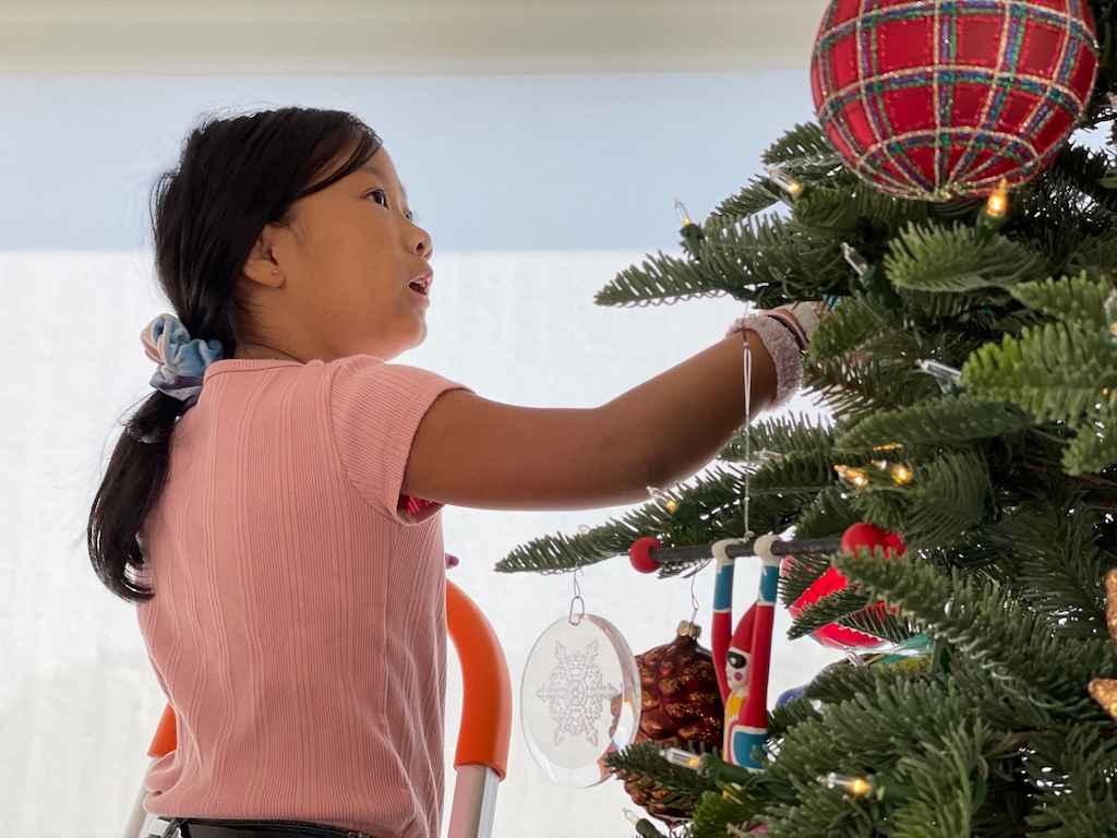Grandchild decorates a Christmas tree.