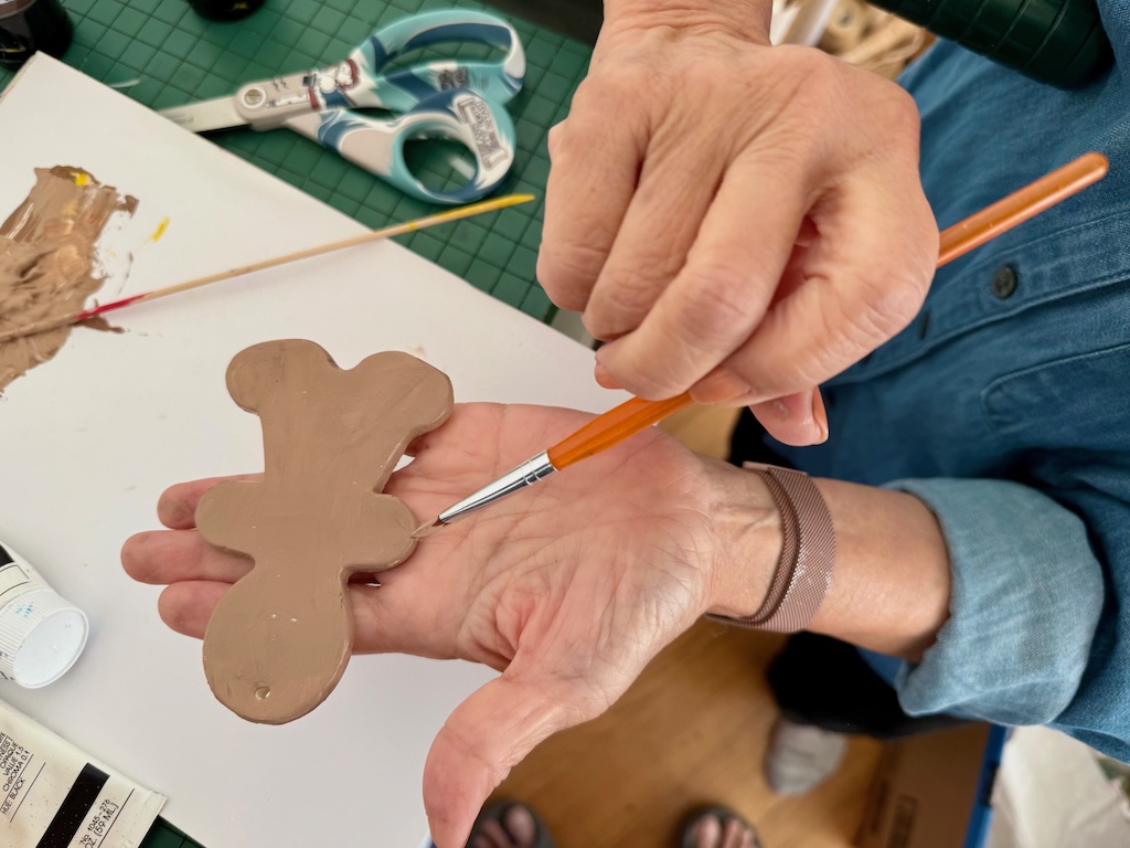 To paint a Christmas cookie Christmas ornament, hold the ornament in the palm of your hand to paint the edges.