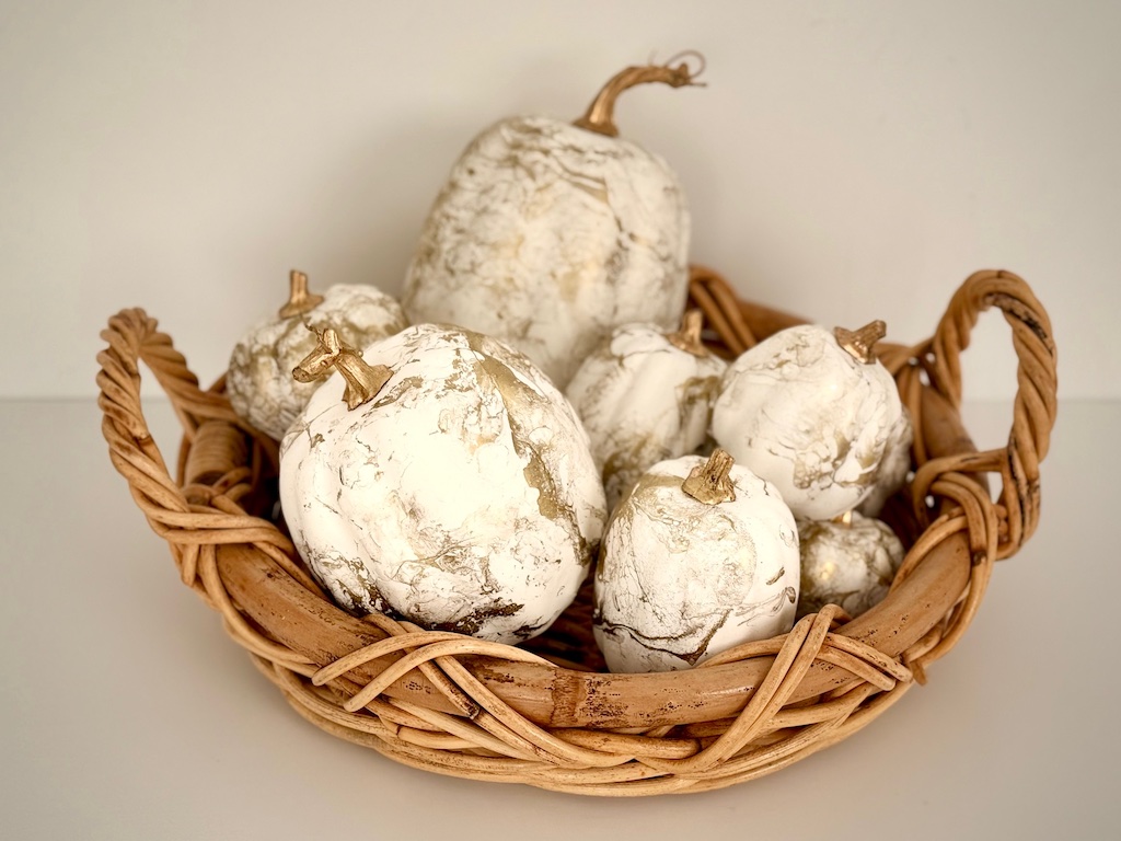 Painted pumpkins arranged in a basket.