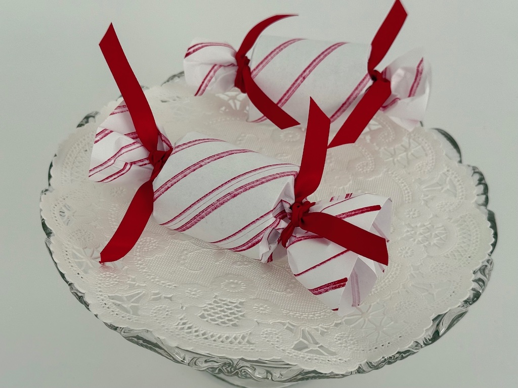 Peppermint candy Christmas ornaments are toilet paper roll halves wrapped in striped printer paper.