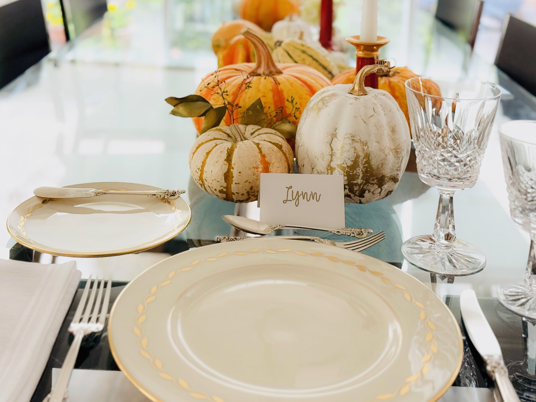 A table-setting idea: gold painted pumpkins mixed with striated pumpkins and gourds, with gold-sprayed eucalyptus leaves.