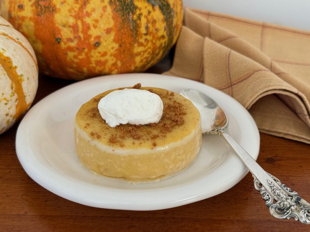Unmolded panna cotta with crushed cookie crumbs and whipped cream.