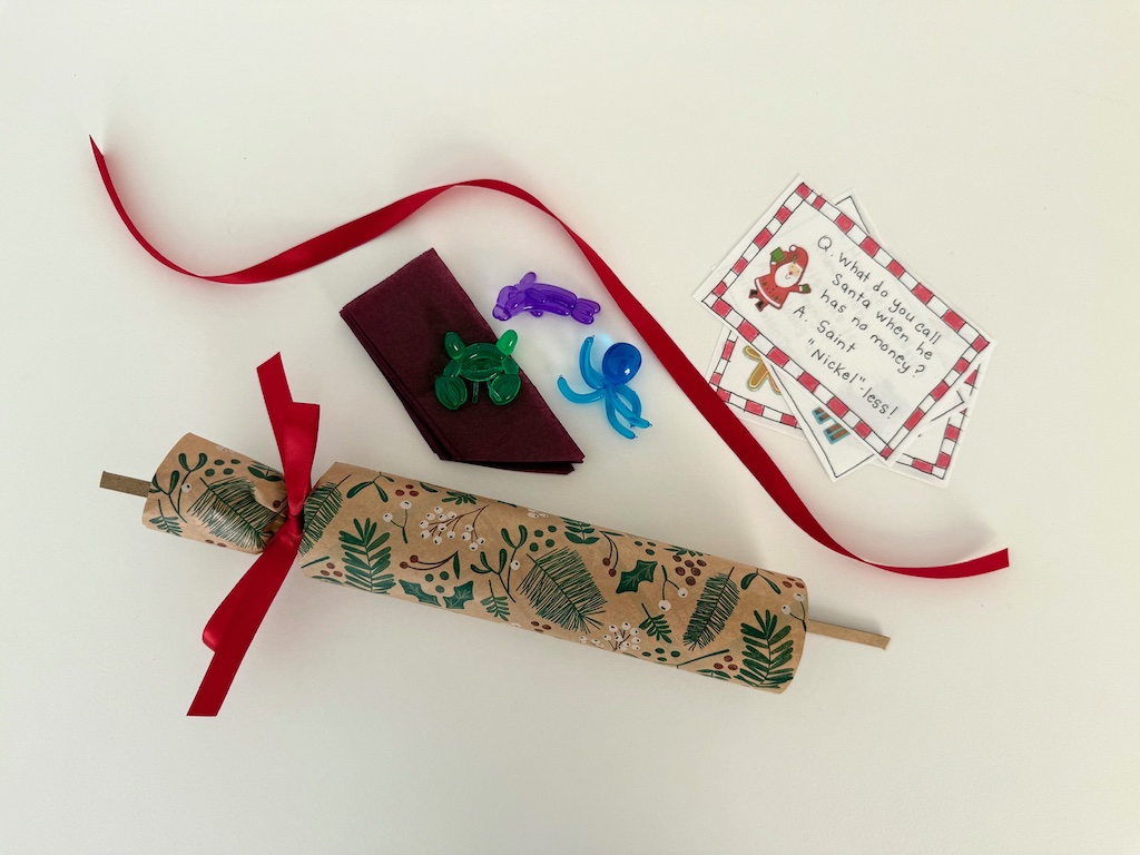 The Christmas cracker is tied at one end. The crown, gift, and riddle will be stuffed in the cracker and tied with ribbon.