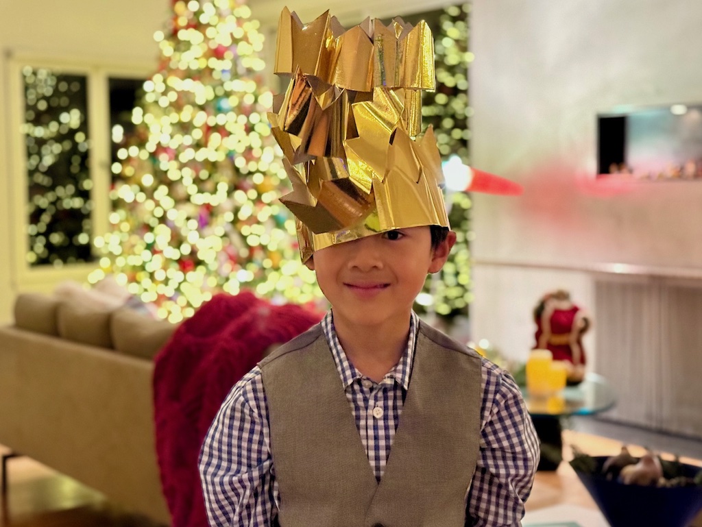 Child wearing all the crowns after dinner, stacked on his head, for the fun of it.