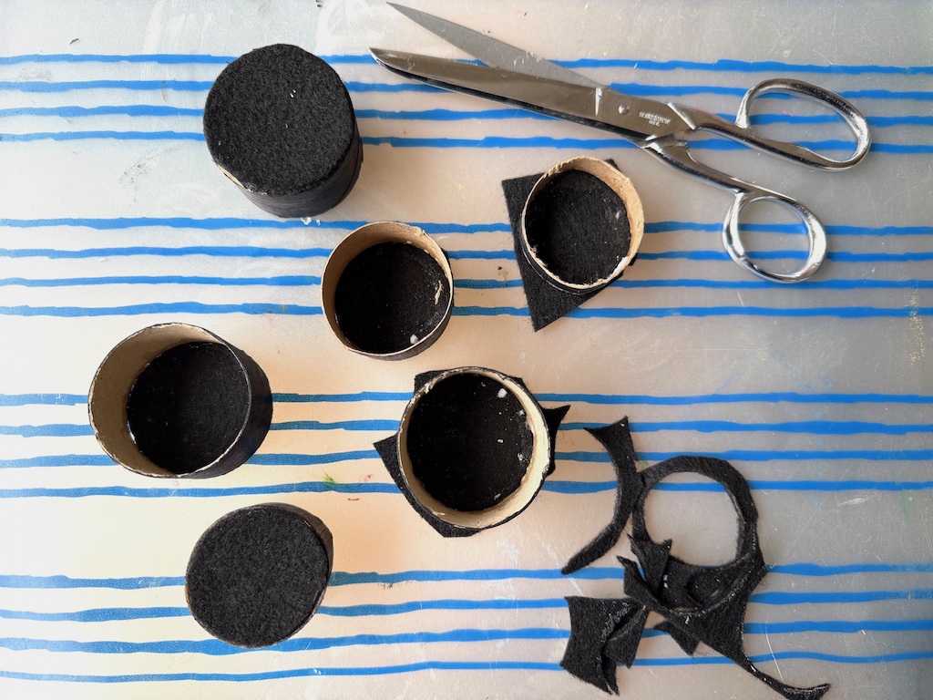 To make the top of the hat, trace the toilet paper roll on black felt, cut out, and glue in place.