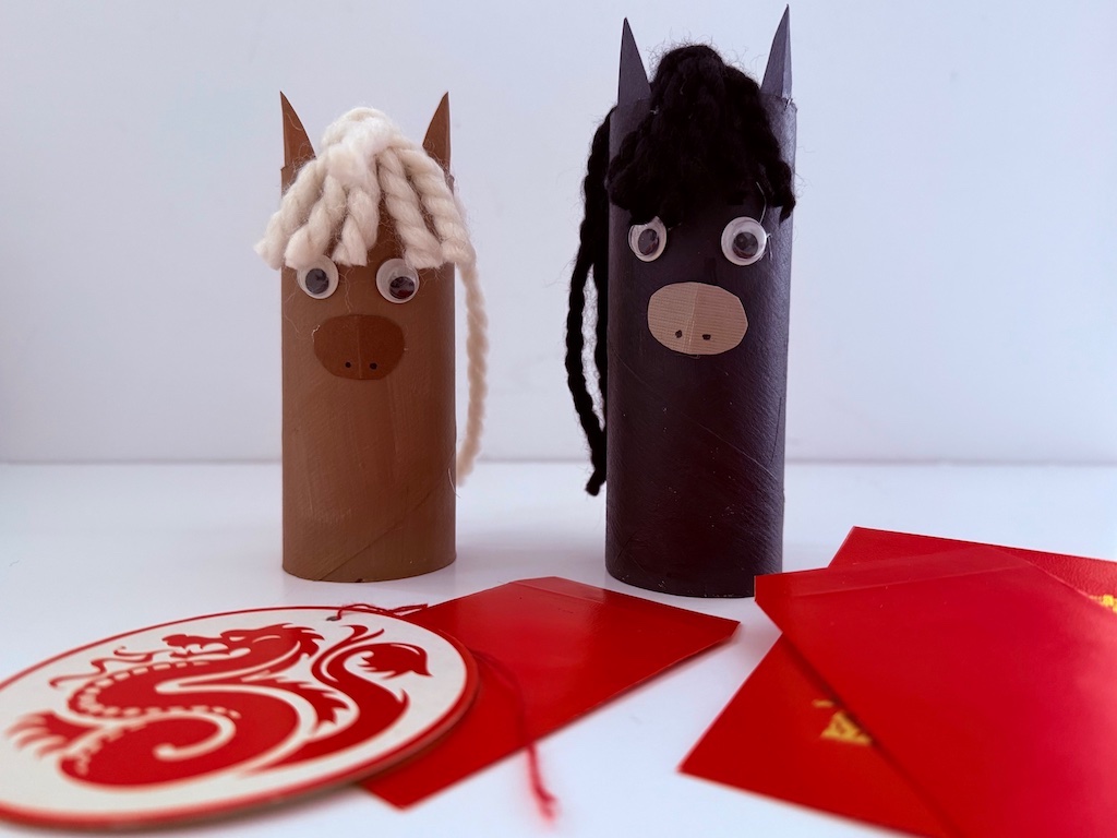 Two horses are made from painted toilet paper rolls, cconstruction paper, and yarn scraps.