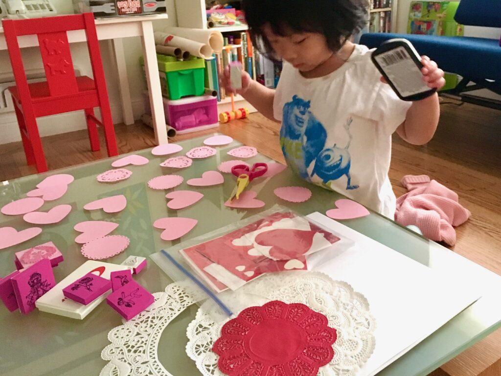 A four-year-old makes Valentines with doilies and hearts.