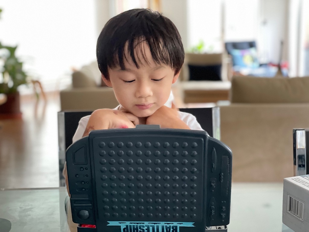 Child playing Battleship. Learn some tricks to win at board games.