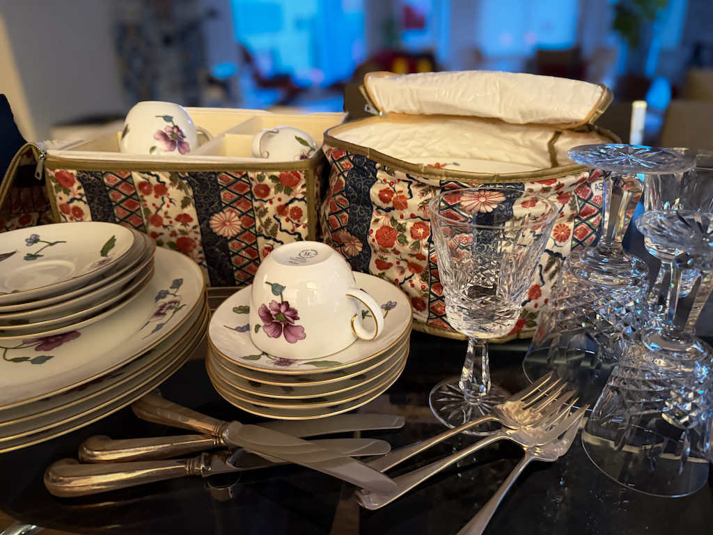 Fine china, crystal, and silverware on a table to be packed up for giving away.