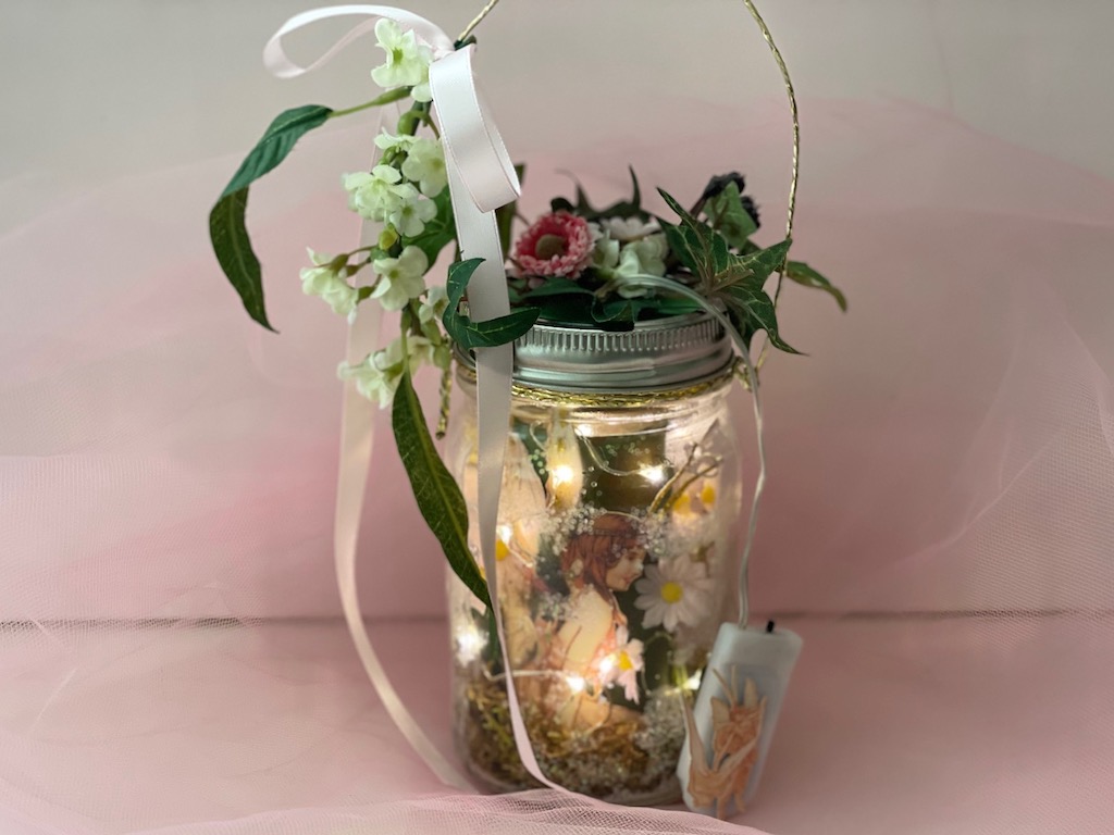 A fairy lantern is made from a mason jar, filled with fairy lights and decorated with artificial flowers and leaves. The perfect way to banish winter doldrums on a cold, dark day.