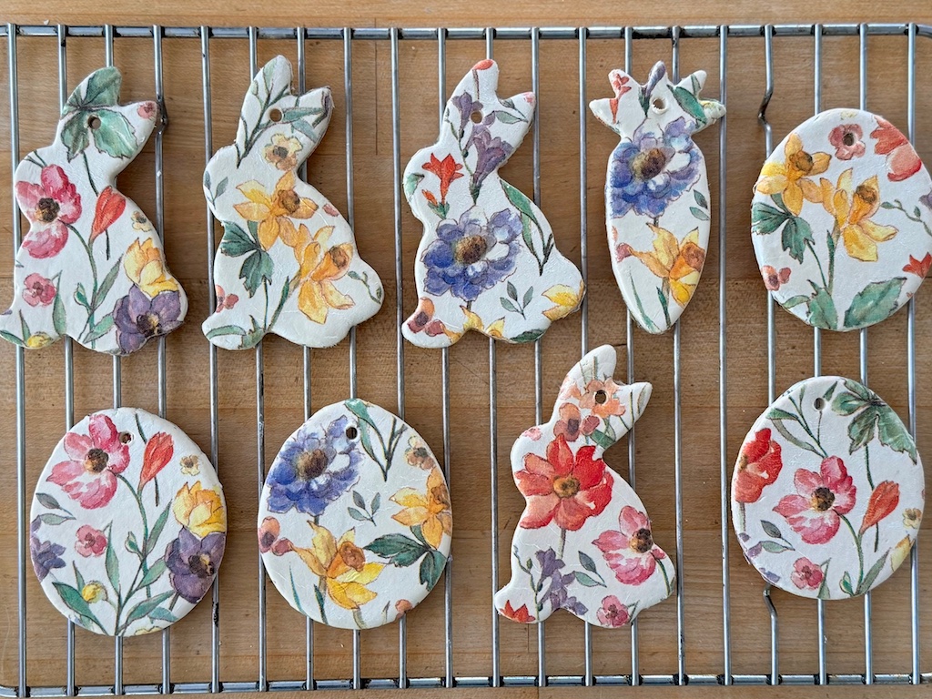 Easter ornaments on a drying rack. Bunnies, eggs, and a carrot are covered with floral designs from a paper napkin.