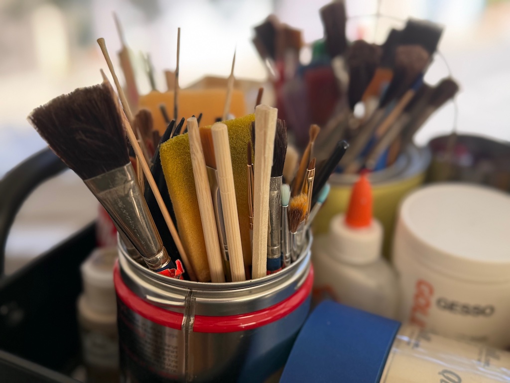 Washed and dried disposable chopsticks sit in a container with paint brushes. Use the chopsticks to stir paint and for other art projects.