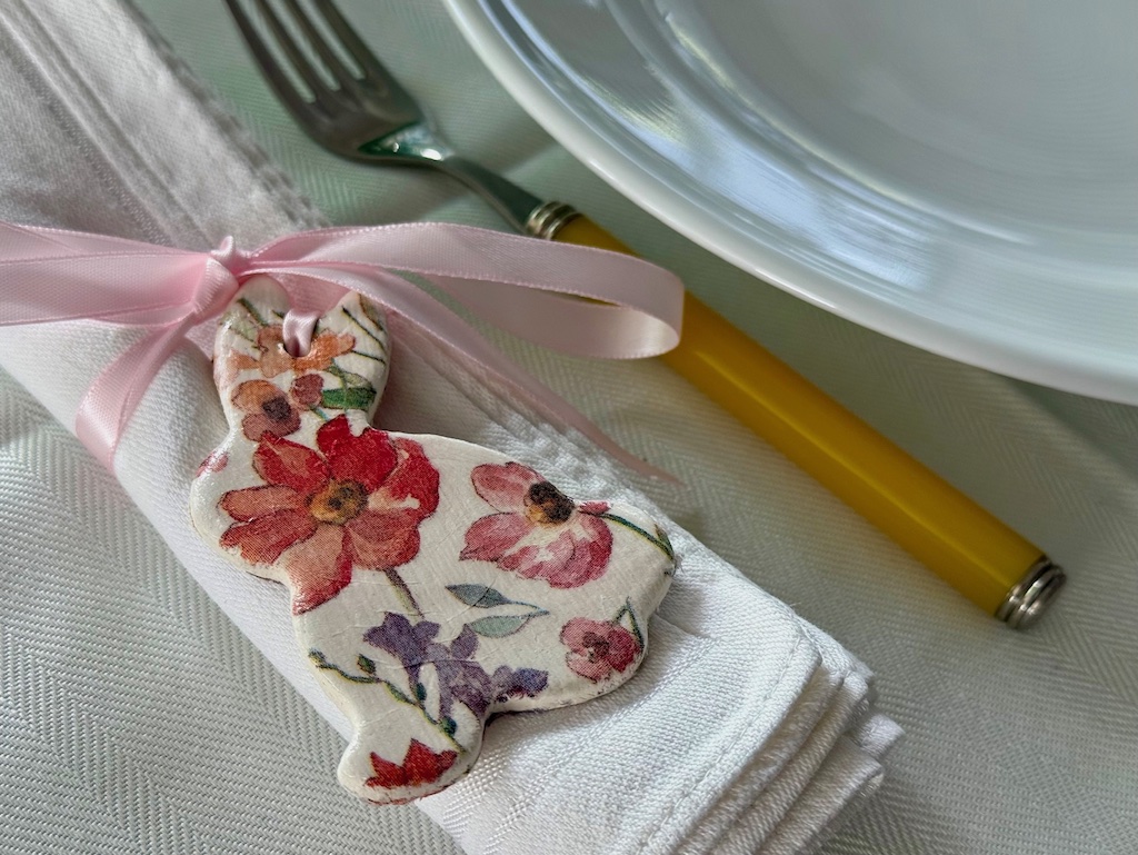 Easter bunny from air dry clay is tied to a napkin with ribbon for a casual Easter brunch.