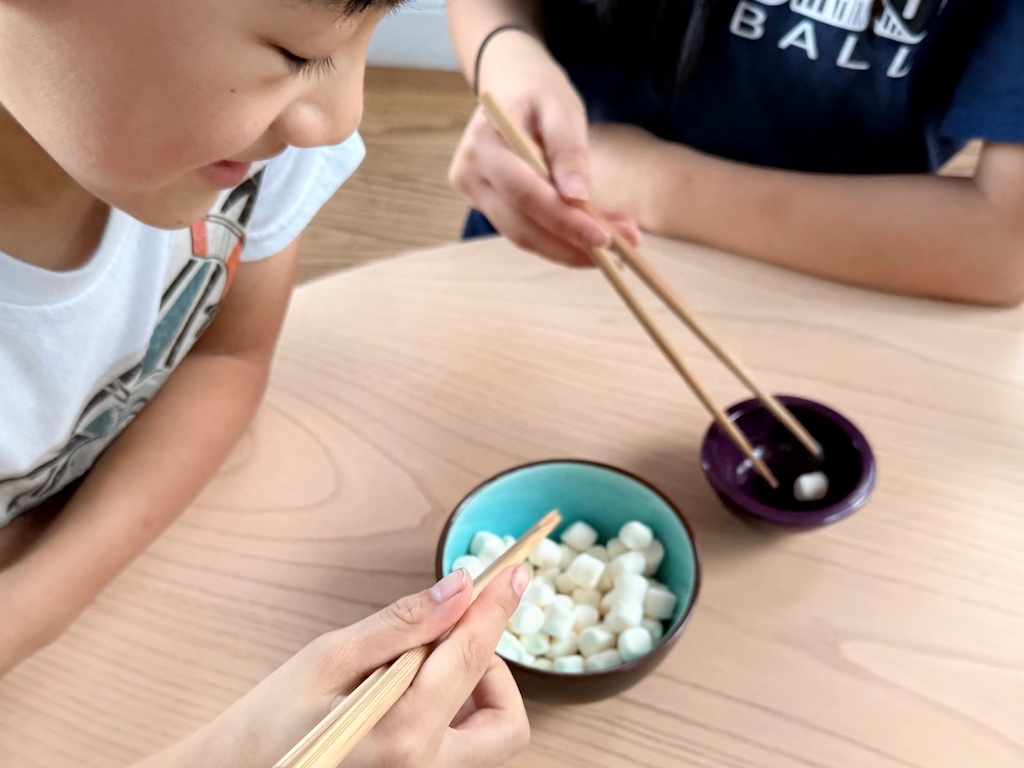 Kids take marshmallows from the bowl using chopsticks. The one who gets the most marshmallows wins.