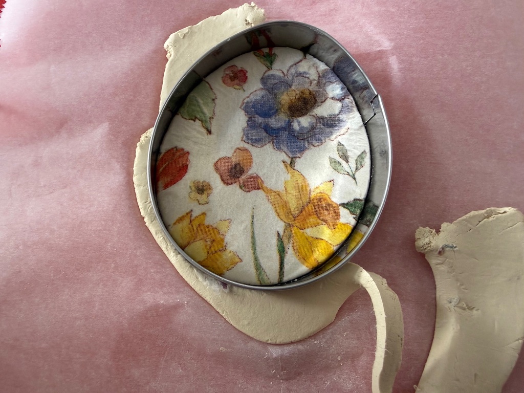 From the right side, hold the cookie cutter down on the work surface and peel the clay away from the cutter.