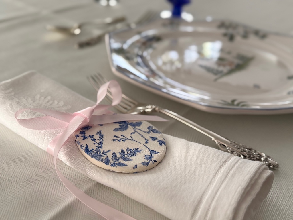 Easter egg from air dry clay is tied to napkin with ribbon for an elegant Easter table.