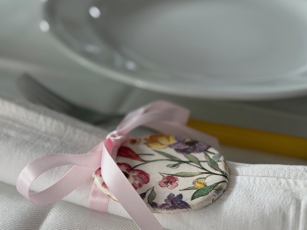 Easter egg from air dry clay is tied to a napkin with ribbon for a casual Easter brunch.