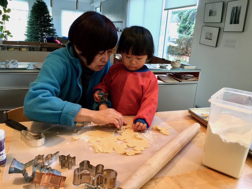 A two-year-old child and grandma make Christmas cookies together. Today, the child at 12, still enjoys this annual activity with grandma.