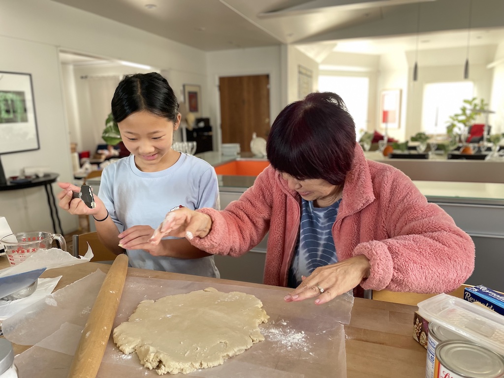 Grandmother and child making pie together. Helping to care for a grandchild might help to keep the caregiver's brains healthy.