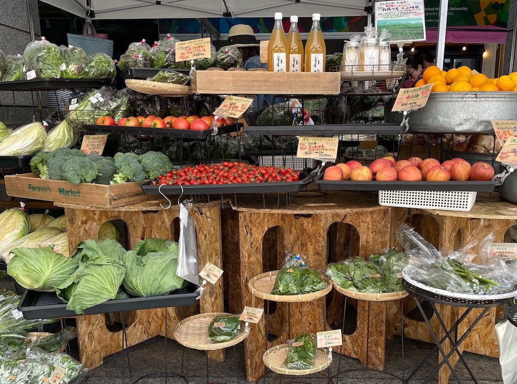 Farmers market in Tokyo. Produce is displayed on tiered tables.