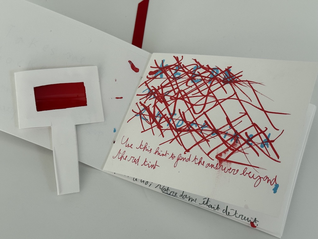 In this puzzle, the sentiment is written in blue, then scribbled over in red. You can only read the sentiment by hovering over it using a transparent red plastic object to see through the red scribbles.