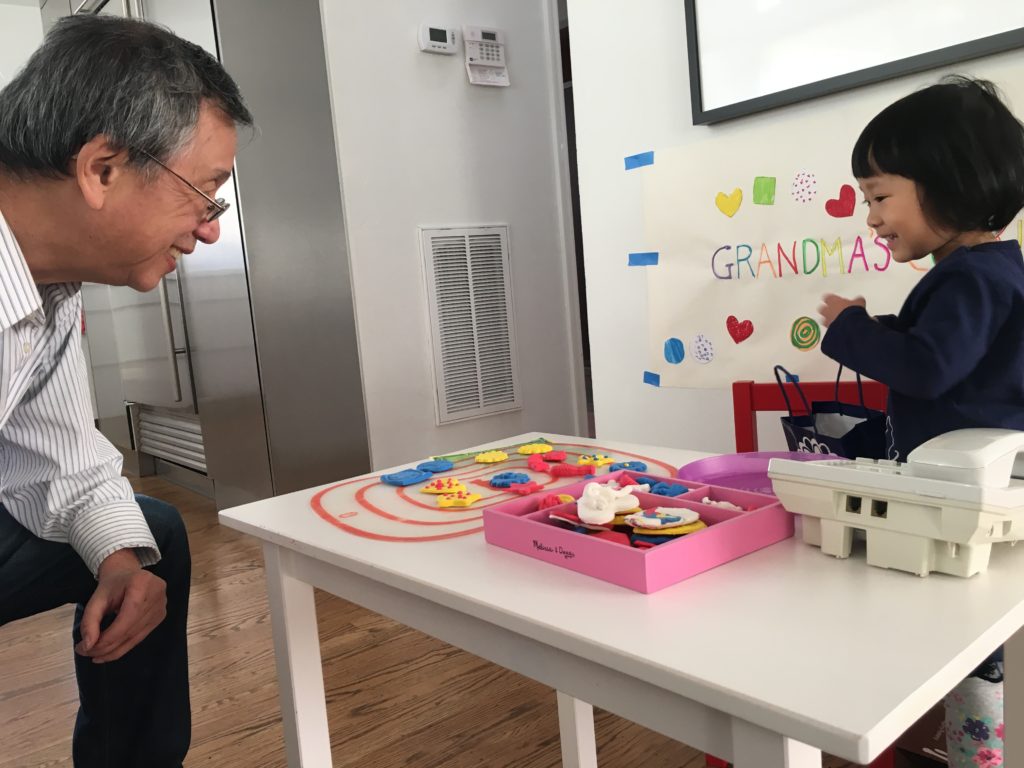 Child sells air dry cookies to her grandpa as they play the cookie shop game.