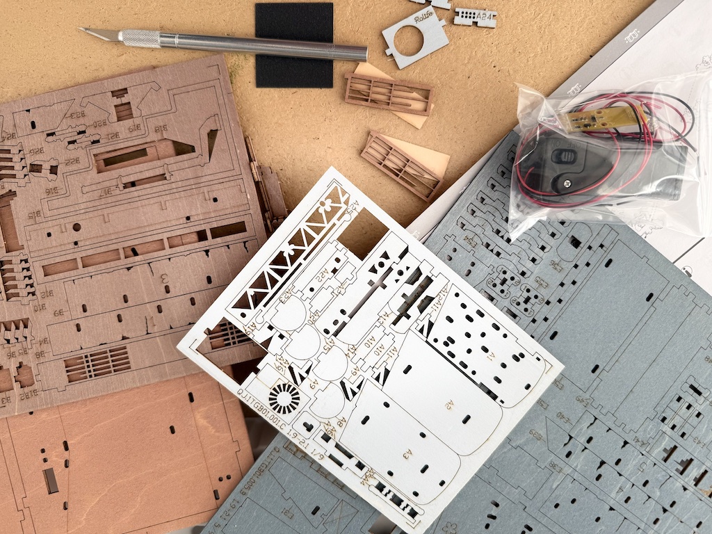 Components to make a book nook kit are laid out on a table for assembly. Each tiny piece pops out; you construct the scene following detailed instructions.