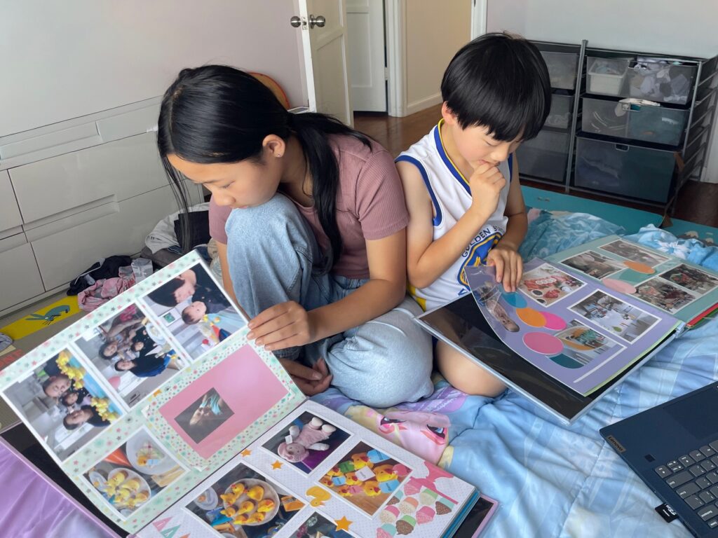 Children look at their scrapbooks made by grandma, featuring their first year of life.
