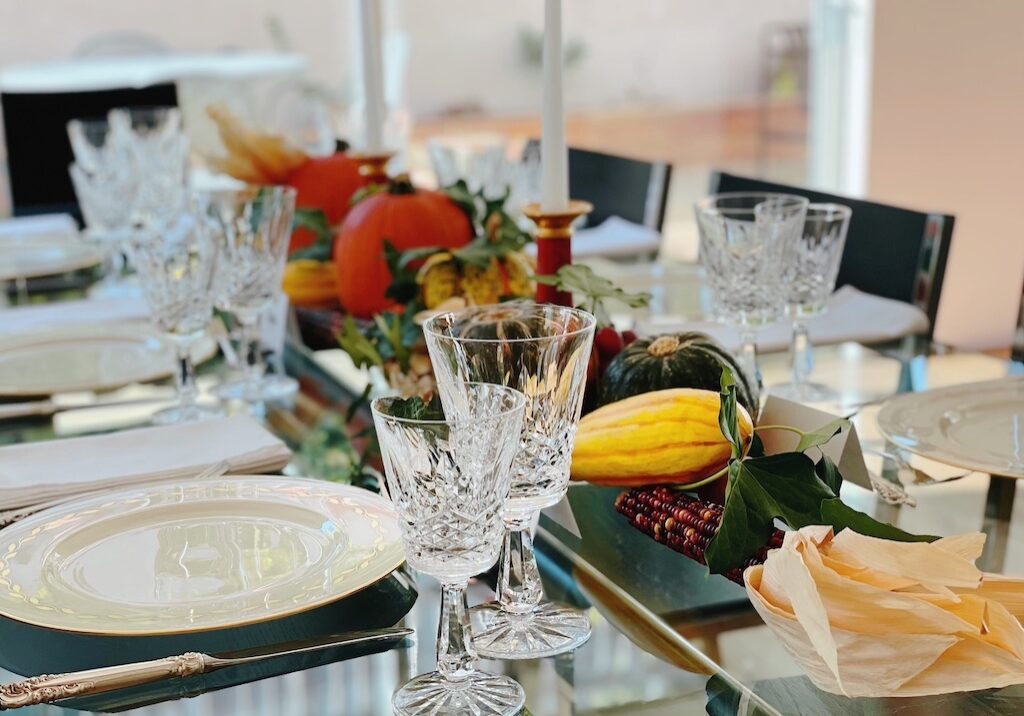 Thanksgiving table centerpiece is made with a row of fall produce and icy intertwined.