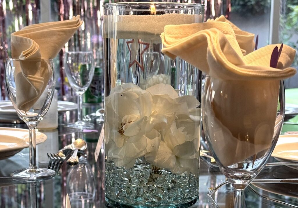 Roses are submerged in water and topped with a layer of candle sand, ready to be lit.