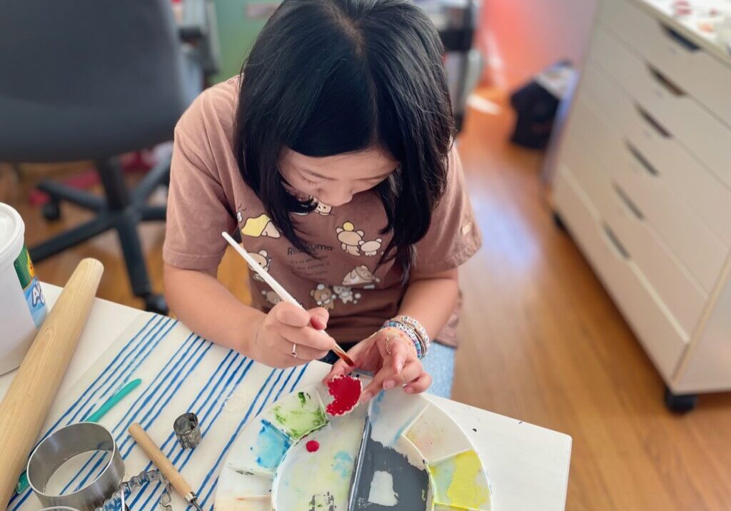 Child paints air dry clay to make a ring holder from air dry clay for a last-minute Mother's Day gift.