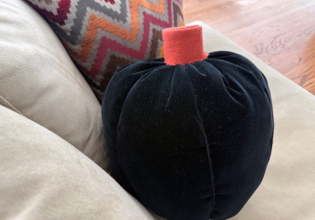 Make a simple pumpkin pillow with fabric, yarn, and felt.