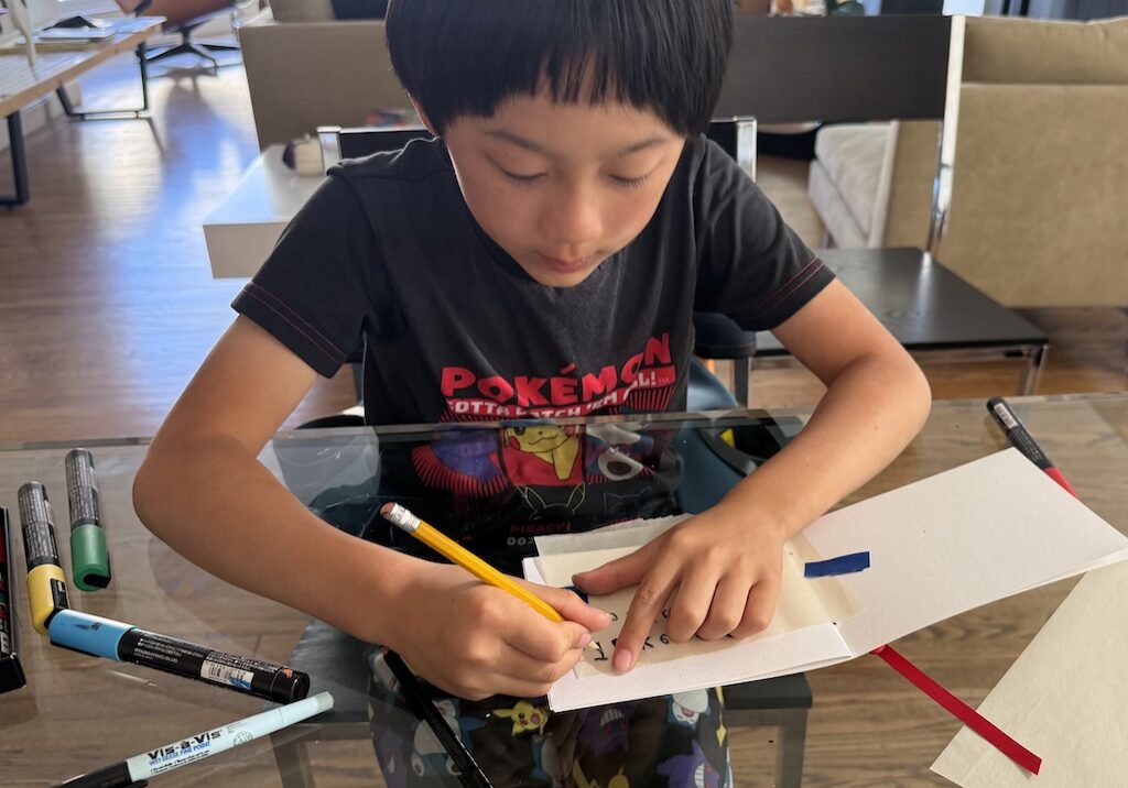 Child traces over tissue paper message flipped over to create mirror writing.
